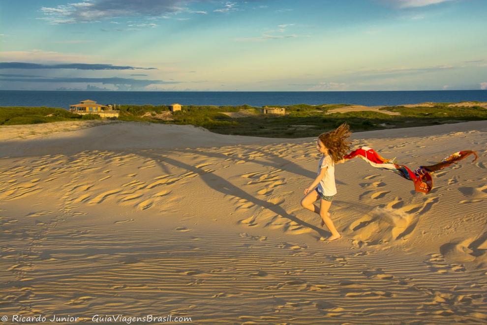 Imagem de criança brincado nas dunas da praia de Itaúnas